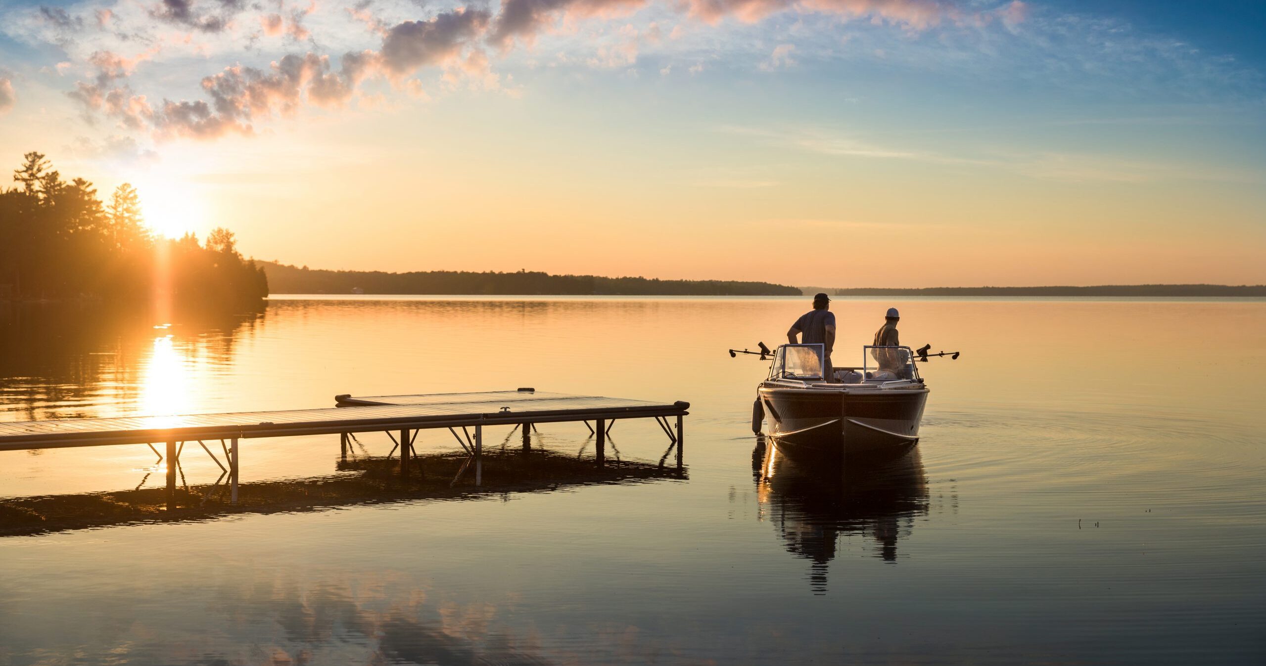 two fisherman fish from a small boat next to a dock
