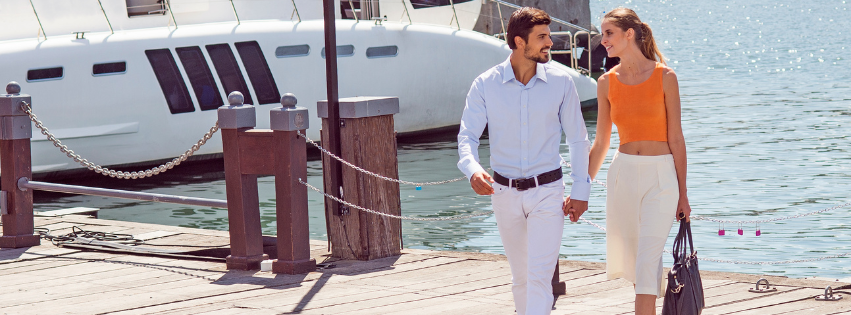 a couple walks on a dock away from a boat