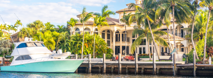 a large yacht is docked in a canal outside a large Floridian home