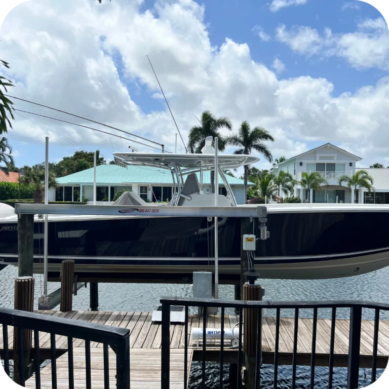 a boat sits on a boat lift at a dock with palm trees behind it