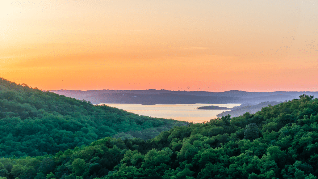 sunset over a lake with small mountains around it