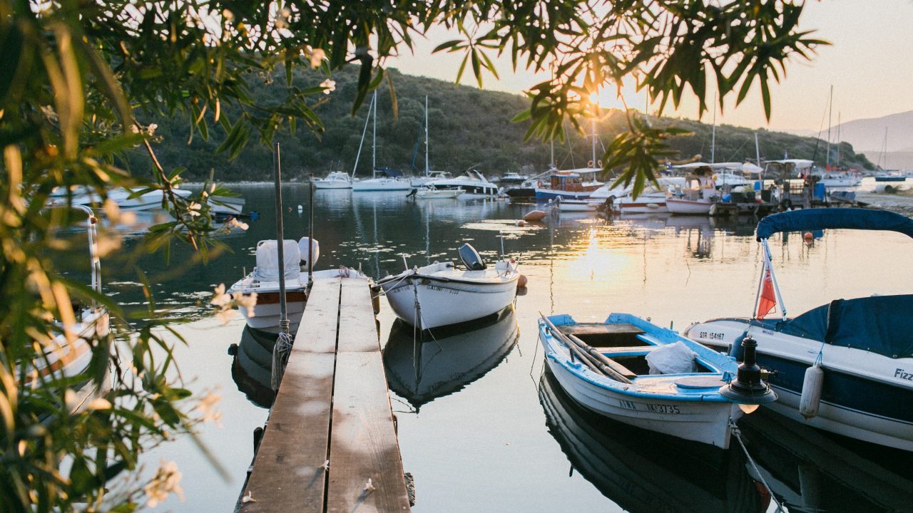 A picturesque sunset casts a warm glow over boats docked at the harbor, embodying Dockshare's ethos of respectful sharing.