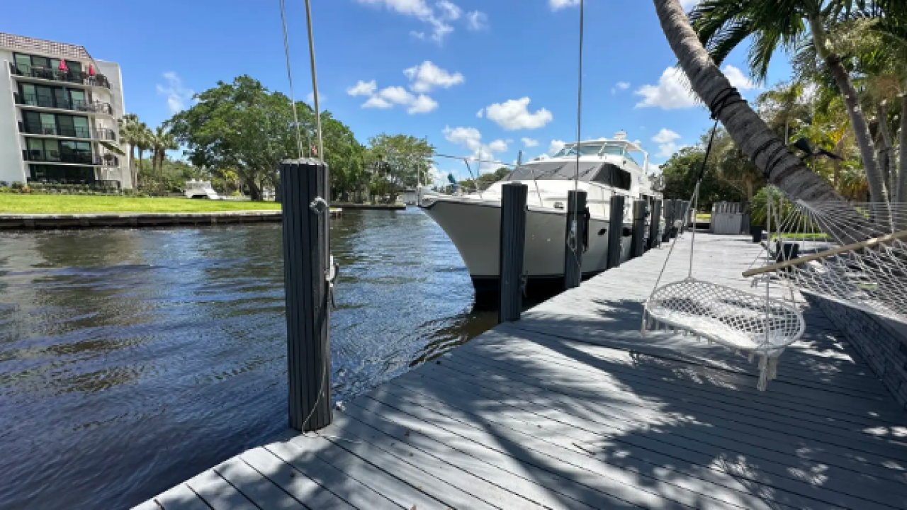large boat docked next to a private dock on a Florida canal with a hammock and palm tree